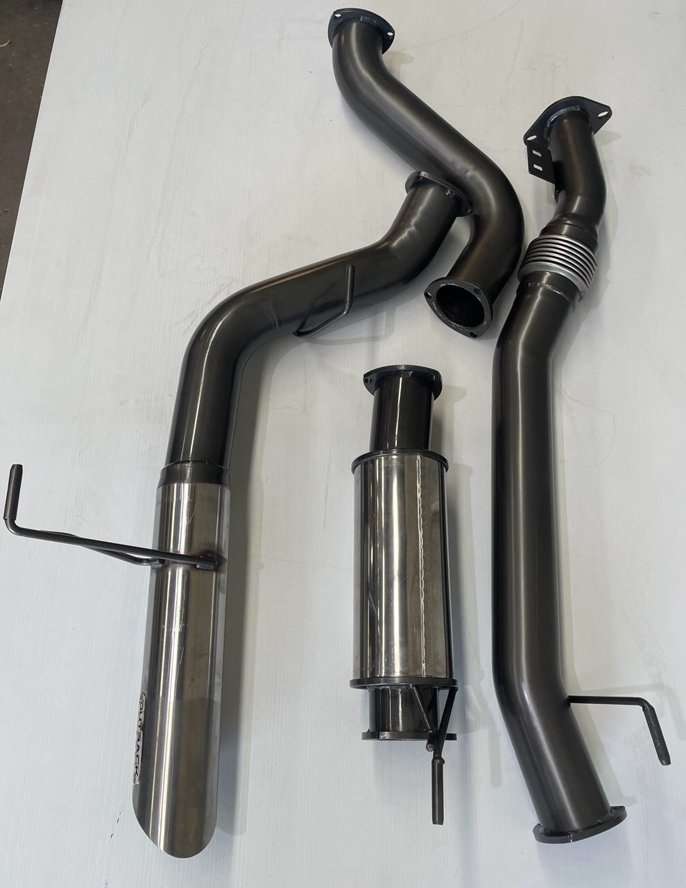Image of a 3.5 inch Outback Exhausts DPF back system designed for a 300 Series Toyota Landcruiser 3.3L V6 Turbo Diesel Wagon. The system features mandrel-bent 409 stainless steel pipes with welded flanges at both ends and mounting brackets. One of the pipe includes a resonator while another features a tail tip. The system is displayed against a transparent background. SKU OE4712-S35.